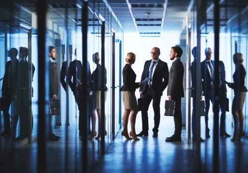 Three office workers talking in corridor of business center